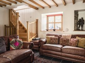 A living room with sofas and stairs at Y Bwthyn in Llangrannog
