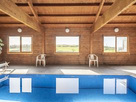 An indoor pool area with windows and chairs at Y Bwthyn in Llangrannog