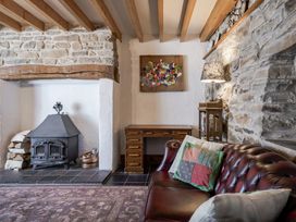 A living room with a fireplace, sofa, and desk at Coach House in Llangrannog