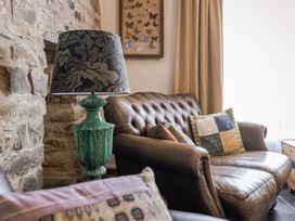 A living room with a sofa, lamp and decor at Coach House in Llangrannog