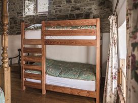 A bunk bed with green bedding and a lamp in the bedroom at Coach House in Llangrannog