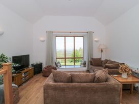 A living room with brown sofas a wooden table a television and a large window at Newlands Barn in Wellington