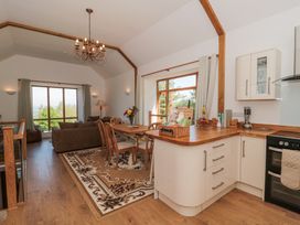 An open plan kitchen and dining area with wooden furniture and large windows at Newlands Barn in Wellington