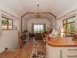 An open living area with wooden flooring and furniture including a dining table and chairs a sofa and a window with curtains at Newlands Barn in Wellington