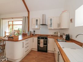 A kitchen with white cabinets wooden countertops a black oven a stainless steel hood and a white sink at Newlands Barn in Wellington