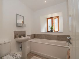 A bathroom with a bathtub sink toilet towel and a window with a plant on the sill at Newlands Barn in Wellington