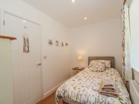 A small bedroom with a single bed a bedside table with a lamp folded towels on the bed and a window with floral curtains at Newlands Barn in Wellington