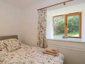 A bedroom with a bed with floral bedding next to a window with matching curtains and folded towels near Newlands Barn in Wellington