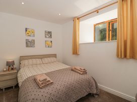 A bedroom with a bed with striped bedding and folded towels on a quilted blanket a nightstand with a lamp and alarm clock and four floral paintings on the wall at Newlands Barn in Wellington