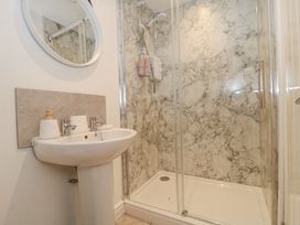 A bathroom with a pedestal sink and a shower enclosure with marble-patterned wall panels at Newlands Barn in Wellington