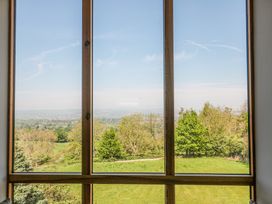 A window with wooden frame showing trees and grassy field outside at Newlands Barn in Wellington