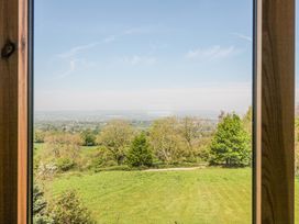 A view of green fields trees and distant hills through a wooden framed window at Newlands Barn in Wellington