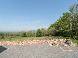 An outdoor area with a gravel ground a low stone wall trees and a wooden planter at Newlands Barn in Wellington
