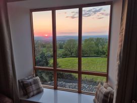 A window seat with cushions overlooking trees and fields at sunset at Newlands Barn in Wellington