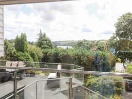 A balcony with patio furniture overlooking trees and water at Treliance in Truro