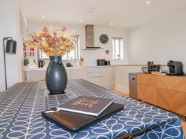 A kitchen with a table covered with a patterned tablecloth and a vase of flowers on it at Ebbtide in Newquay