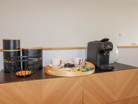 A countertop with a coffee machine tea and coffee canisters cups and a tray with snacks at Ebbtide in Newquay