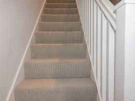 A carpeted staircase with white railing on the side at Ebbtide in Newquay