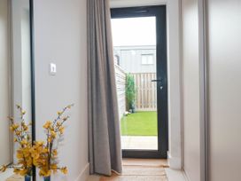 A door with grey curtain leading to a small garden with a wooden fence and plants at Ebbtide in Newquay
