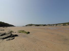 A sandy beach with rocks and low cliffs under a clear sky at Ebbtide in Newquay