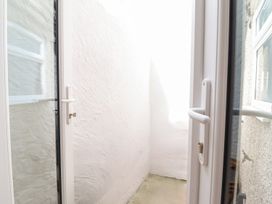 A small enclosed outdoor area with white textured walls and a concrete floor seen through a glass door at 3 Rosemary Lane in Conwy