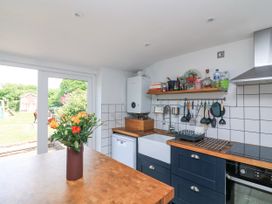 A kitchen with wooden countertops a vase with flowers on the island and a view of a garden at Joymead in Malborough
