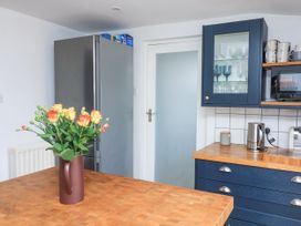 A kitchen with a wooden countertop a vase with flowers a silver refrigerator blue cabinets with glassware a kettle and a toaster at Joymead in Malborough