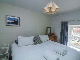 A bedroom with a large bed with white bedding pillows and rolled towels a wooden dresser and a window with blue curtains at Joymead in Malborough