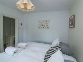 A bedroom with a bed with pillows and rolled towels on it a wall hanging with sea creatures and a framed picture on the wall at Joymead in Malborough