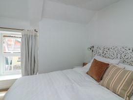 A bedroom with a white bed and decorative headboard two pillows and a curtained window at Joymead in Malborough