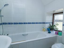 A bathroom with a bathtub shower combination a window with plants and toiletries at Joymead in Malborough