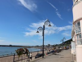 A beach with people walking along the street and buildings at The Well House in Lyme Regis