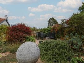 A garden with a dining set and a round sculpture at The Well House in Lyme Regis