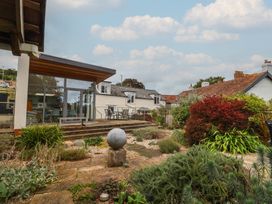 A garden with a stone sculpture, table and chairs at The Well House in Lyme Regis