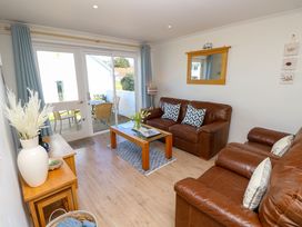 A living room with two brown leather sofas a wooden coffee table and glass doors leading to an outdoor seating area at Cape A9 Norton Near Freshwater
