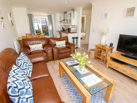 A living room with brown leather sofas a glass coffee table with flowers a wooden dining table and a television at Cape A9 Norton Near Freshwater