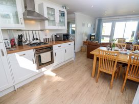 A kitchen with white cabinets wooden countertop dining table with chairs and a living area with sofa and television at Cape A9 Norton Near Freshwater