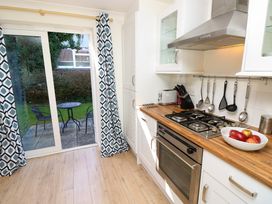 A kitchen with wooden countertop gas stove oven utensils hanging and sliding glass door leading to garden with table and chairs at Cape A9 Norton Near Freshwater
