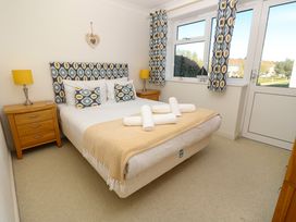 A bedroom with a bed having patterned headboard and cushions bedside tables with lamps and a door with window at Cape A9 Norton Near Freshwater