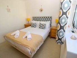 A bedroom with a double bed two bedside tables with lamps and patterned curtains at Cape A9 Norton Near Freshwater