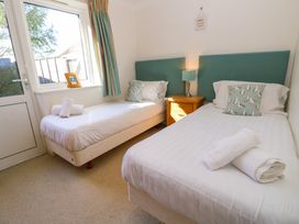 A bedroom with two single beds white linens teal cushions and a wooden nightstand with a lamp at Cape A9 Norton Near Freshwater