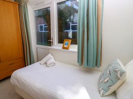 A bedroom with a single bed a wooden wardrobe and a window with curtains at Cape A9 Norton Near Freshwater