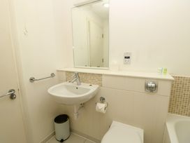 A bathroom with a sink mirror toilet toilet paper on holder and a small trash can at Cape A9 Norton Near Freshwater