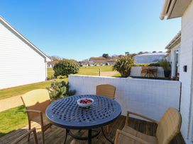 An outdoor patio with a round table and four chairs a bowl with fruit on the table and houses in the background at Cape A9 Norton Near Freshwater