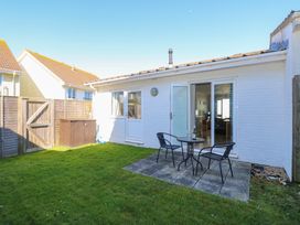 A small backyard with green grass a patio area with a round table and two chairs next to a white brick house at Cape A9 Norton Near Freshwater