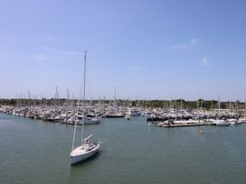 A marina with many docked sailboats and yachts and one sailboat sailing in the water at Cape A9 Norton Near Freshwater