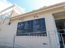 An outdoor menu board on the wall of a light-colored wooden building at The Hut in Colwell Bay