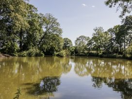 A pond surrounded by trees with reflections at The Lodge in 