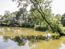 A pond with a tree and a cabin in the background near the water at The Lodge in 