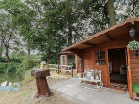 A cabin with wooden deck and bench at Carps Well Lodge Hatton near Shrewley